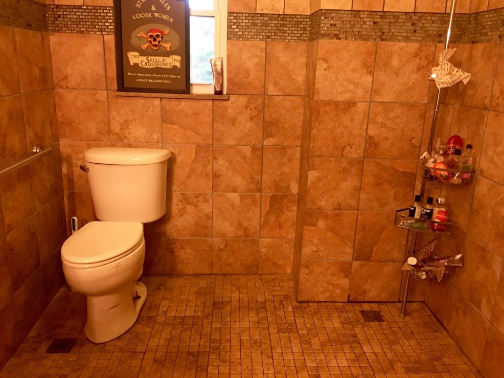 Toilet in a wet bath with a 3 foot wide space beside it to accommodate a wheelchair.